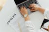A woman using a laptop alongside a contract document on a desk, emphasizing business and legal themes.